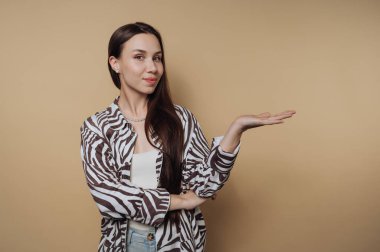 Zebra desenli tişörtlü kadın bej arka planda tek eliyle hareket ediyor..