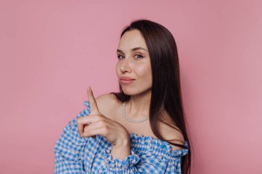 Mavi kareli omuzlu kadın pembe arka planda poz veriyor..