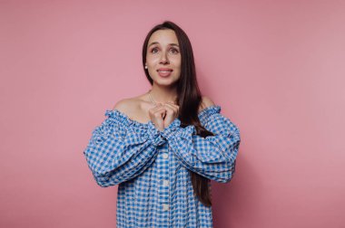 Mavi omuzlu kadın pembe arka planda umutlu görünüyor..