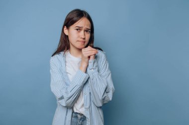 Endişeli bir ifadeyle ellerini sıkan genç bir kadın..