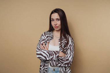Uzun saçlı, zebra desenli gömlekli, kolları çapraz, tarafsız bir geçmişi olan genç bir kadın..