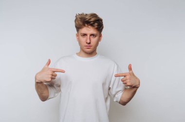 Beyaz tişörtlü genç adam arka planda kendini gösteriyor..