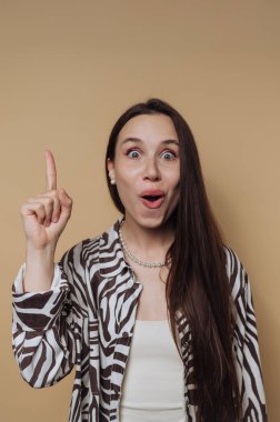 Uzun saçlı şaşırmış bir kadın bej arka planda yukarıya bakıyor..