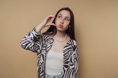 Bej arkaplana karşı neşeli bir yüz ifadesi takınan kadın..