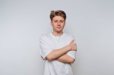 Beyaz tişörtlü genç adam arka planda duruyor..