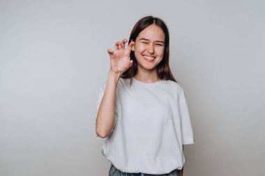 Genç bir kadın elinde pençe hareketi yapıyor, gülümsüyor..