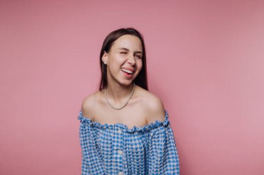 Mavi omuzlu genç bayan pembe arka planda gülüyor..