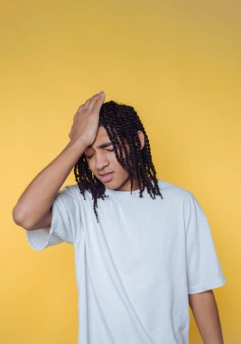 Genç bir insanın portresi hayal kırıklığı içinde başını tutar, bir an için şaşkınlığını gösterir ve sarı arka plan üzerinde düşünür.