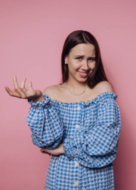 Genç bir kadının portresi ilginç bir şekilde, pembe arka plan üzerinde hem merak hem de tefekkür içeren karmaşık bir ifadeyle hareket eder.