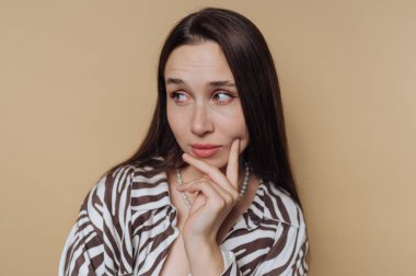 Zebra desenli elbiseli, meraklı genç bir kadının portresi sakin sarı arka planda düşünceli bir ifade sergiliyor.