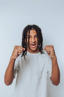 Genç bir adamın portresi sevinçle yumruklarını kaldırır, mutlu bir anı ışık arka planında coşkulu bir ifadeyle kutlar.