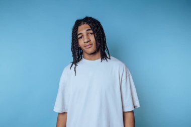 Genç bir adamın portresi, mavi arka planda bir güven karışımı sergiliyor.