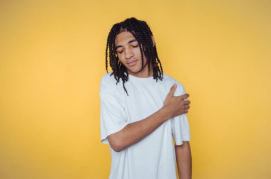 Şık rastalı genç adamın portresi, sarı arka planda sakin bir havayı yansıtıyor.