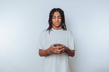 Genç adamın portresi yoğun bir şekilde arka plandaki akıllı telefonuna odaklanır.