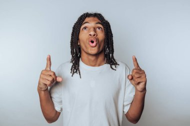 Genç bir insanın portresi coşkulu bir şekilde heyecanı ifade eder, iki eli de hafif arkaplanda yukarıya doğru uzanır.