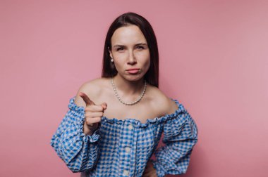 Genç bir kadının portresi iddialı bir şekilde pembe arka plandaki ifadesiyle güçlü bir mesaj iletiyor.