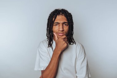 Düşünceli bir yüz ifadesiyle genç bir adamın portresi, çenesini eline dayamış, hafif arka planda derin bir düşüncenin göstergesi.