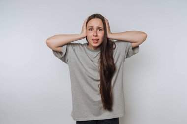 Gri tişörtlü genç bir kadının portresi gözle görülür şekilde hayal kırıklığına uğramış, iç karışıklığı ve duygusal mücadeleyi aydınlık arka planda ifade ediyor.