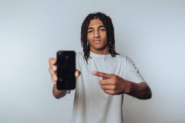 Genç bir adamın portresi arka planda gülümserken akıllı telefonunu gururla sergiliyor.