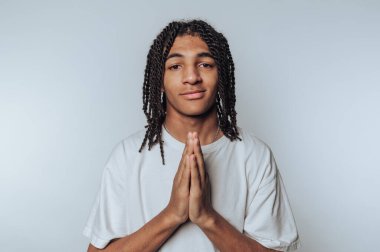 Genç bireyin portresi. Elleri hafif arkaplanda bir dua jestinde.