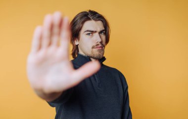 Genç adamın portresi elini kaldırdı, ciddi görünüyordu. Sanki sarı arka planda durması için işaret ediyordu.