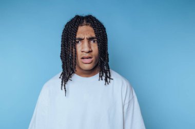 Genç adamın portresi şaşkın görünüyor, mavi arka plandaki şaşkın ifadeleri.