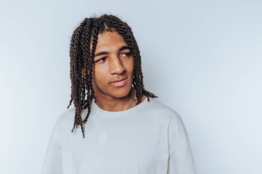 Genç bir adamın portresi derin düşüncelere dalmış bir ifadeyle, ışık arka planında yansıtıcı bir atmosfer yaratıyor.