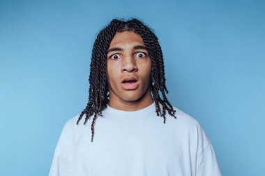 Genç bireyin portresi yoğun bir şok hissi verir. Geniş gözleri mavi arka planda güçlü duygular taşır.