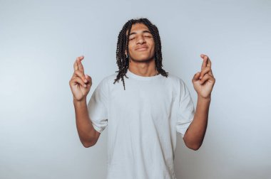 Genç adamın portresi parmaklarını çaprazlarken gülümsüyor, umudu simgeliyor ve arka planda iyi şanslar diliyor.