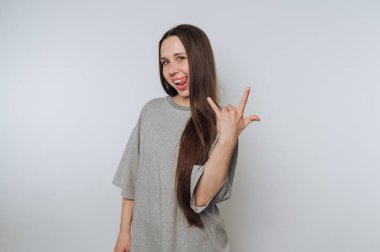 Genç bir kadının portresi, arka planda dilini dışarı çıkarırken eliyle bir kaya işareti hareketi yapıyor.