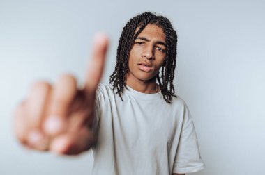 Rastalı genç adam portresi Düşünceli görünürken parmağını kaldırır, hafif arkaplanda düşünceli bir anı aktarır