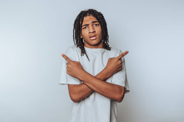 портрет молодого человека выглядит смущенным, указывая в противоположных направлениях с озадаченным выражением лица на светлом фоне