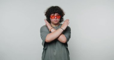 Kıvırcık saçlı, turuncu güneş gözlüğü takan genç bir kadının görüntüleri ışık arka planında bir duraklama hareketi gösteriyor.