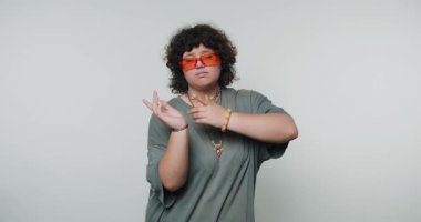 Açık arkaplanda rahat duruşu olan turuncu güneş gözlüğü takan genç bir kadının görüntüleri.