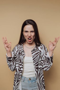 Genç bir kadın, modaya uygun siyah ve beyaz desenli gömlek ve günlük kot pantolon giyerken yoğun bir ifadeyle hayal kırıklığını gösteriyor. Dramatik duruşu duyguları canlı bir şekilde yakalıyor..