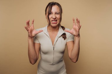 Bir fitness meraklısı, güçlü ve kararlı bir ifadeyle poz verir. Tarafsız arka plan, bireyin vahşi tavrı ve atletik tarzına odaklanmayı vurguluyor..