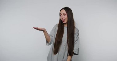 Uzun saçlı, gri tişörtlü, tek eliyle hareket eden genç bir kadın..