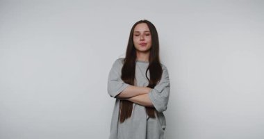 Uzun saçlı tatminsiz bir kadın kollarını kavuşturuyor, tarafsız bir ifade..