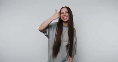 Gri tişörtlü, uzun saçlı, sürpriz yapan genç bir kadın..