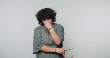 Üzgün, kıvırcık saçlı, gözlüklü, düşünceli bir genç..