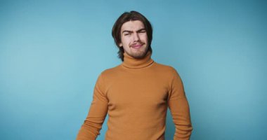 Turuncu balıkçı yakalı bir adam mavi arka planı düşünüyor.