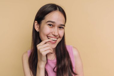 Bej arka planda pembe bluzlu gülümseyen kadın.