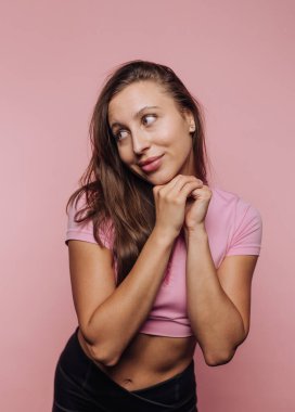 Pembe bluzlu kadın pembe arka planda poz veriyor..