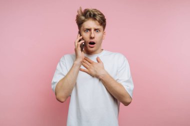 Pembe arka planda telefonla konuşan genç adam şaşırdı..