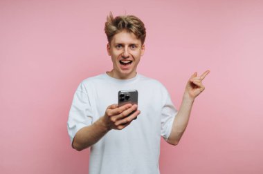 Akıllı telefonu bir şeyi işaret eden heyecanlı genç adam..