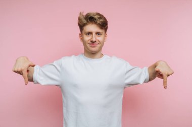 Beyaz gömlekli genç adam iki eliyle aşağıya bakıyor..