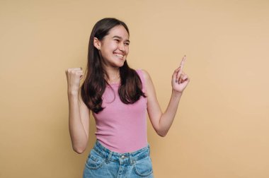 Pembe bluzlu ve kot pantolonlu genç kadın gülümseyerek kutluyor..