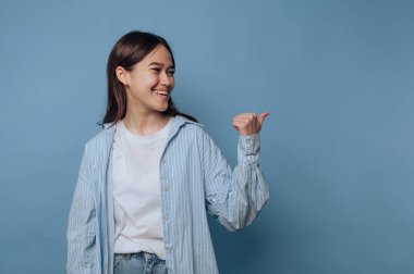 Gülümseyen kadın mavi arka planda yan tarafı işaret ediyor..
