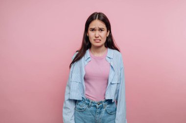 Pembe arka plana karşı kafası karışmış genç bir kadın..