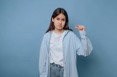 Küçük boylarda, mavi arka planda parmakları olan genç bir kadın..